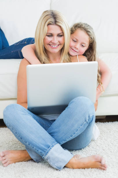 istock Mother sitting on the floor while her daughter hugging her from the sofa 828551286