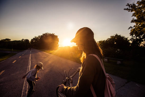 Mother and daughter playing on the bicycle lane at sunset