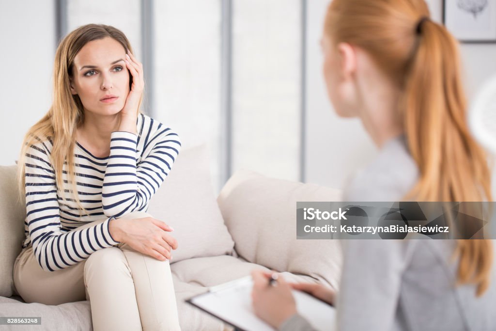 Mental health and counseling concept Mental health and counseling concept, psychologist listening to depressed female patient and writing down notes Psychotherapy Stock Photo