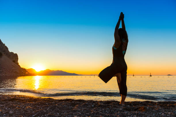 istock Practicing yoga and meditation in summer on beach 828563362