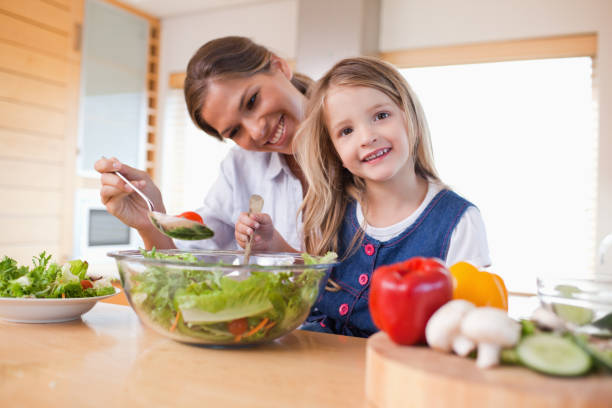 istock Happy mother and her daughter preparing a salad 828568840