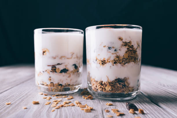 istock Yogurt with granule in cups on white table and on black background close-up 828571338