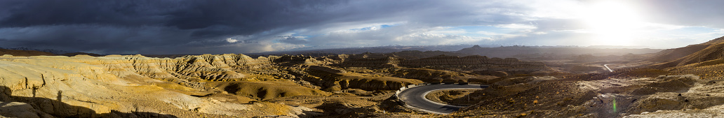 A panoramic shot of an impressive canyon with a vibrant blue sky filled with clouds in the background