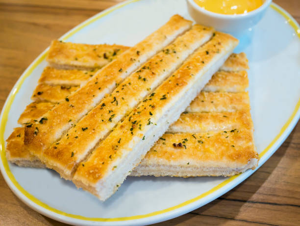 istock Fresh breadsticks served with dip sauce on white plate 828574844
