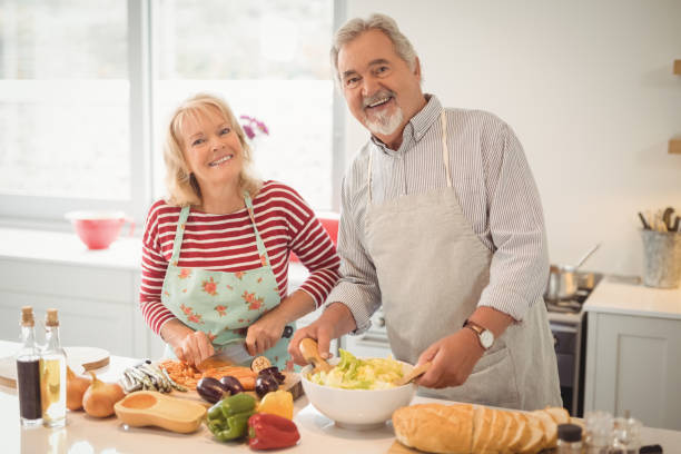 istock Smiling senior couple preparing salad in kitchen 828575984