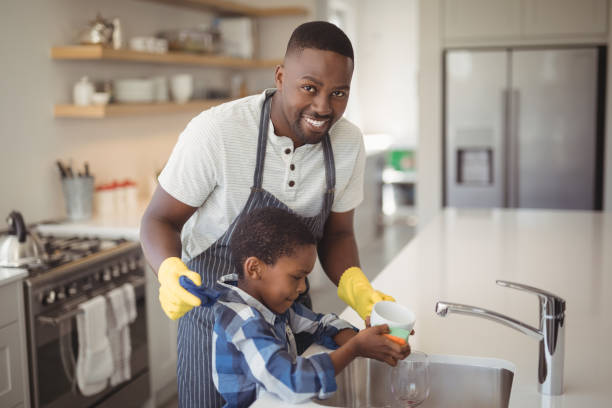 istock Smiling father and son cleaning cup in kitchen 828592464