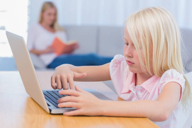 istock Little girl using laptop while her mother is reading on the couch 828605748
