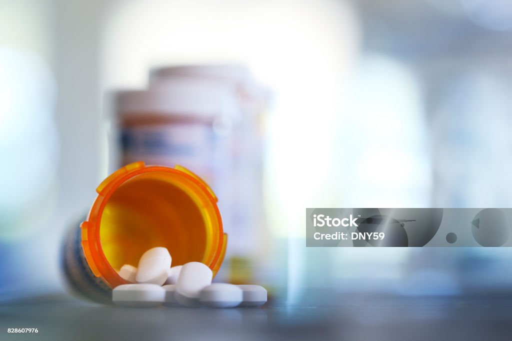 Pills Pour Out Of Prescription Medication Bottle Onto Kitchen Counter Pills pour out of a prescription medication bottle onto a kitchen counter.  Several other pill bottles stand out of focus in the background. Prescription Medicine Stock Photo