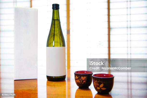 Japan Blank Sake Bottle And Box With Lackered Cups In Front Of Paper Doors Stock Photo - Download Image Now