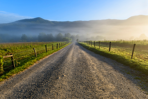 Rural road surrounded by mountains and fields  on summer morning - Great Smoky Mountains National Park.