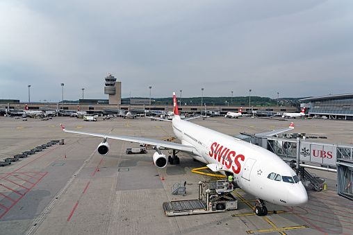 Zurich Airport with Tower and Swiss Aircraft loading Luggage.