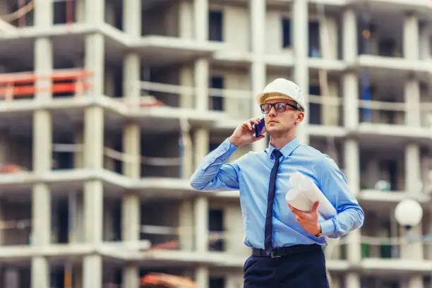 Construction engineer at the construction site talking mobilephone