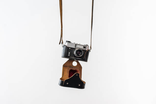istock Vintage film camera in a leather case hanging on straps on a white background 828714654