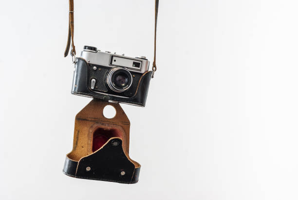 istock Vintage film camera in a leather case hanging on straps on a white background 828714888