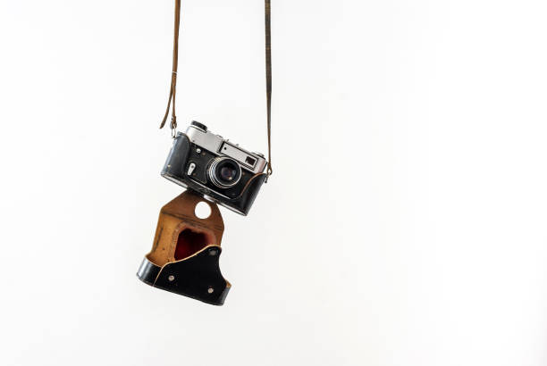 istock Vintage film camera in a leather case hanging on straps on a white background 828715834