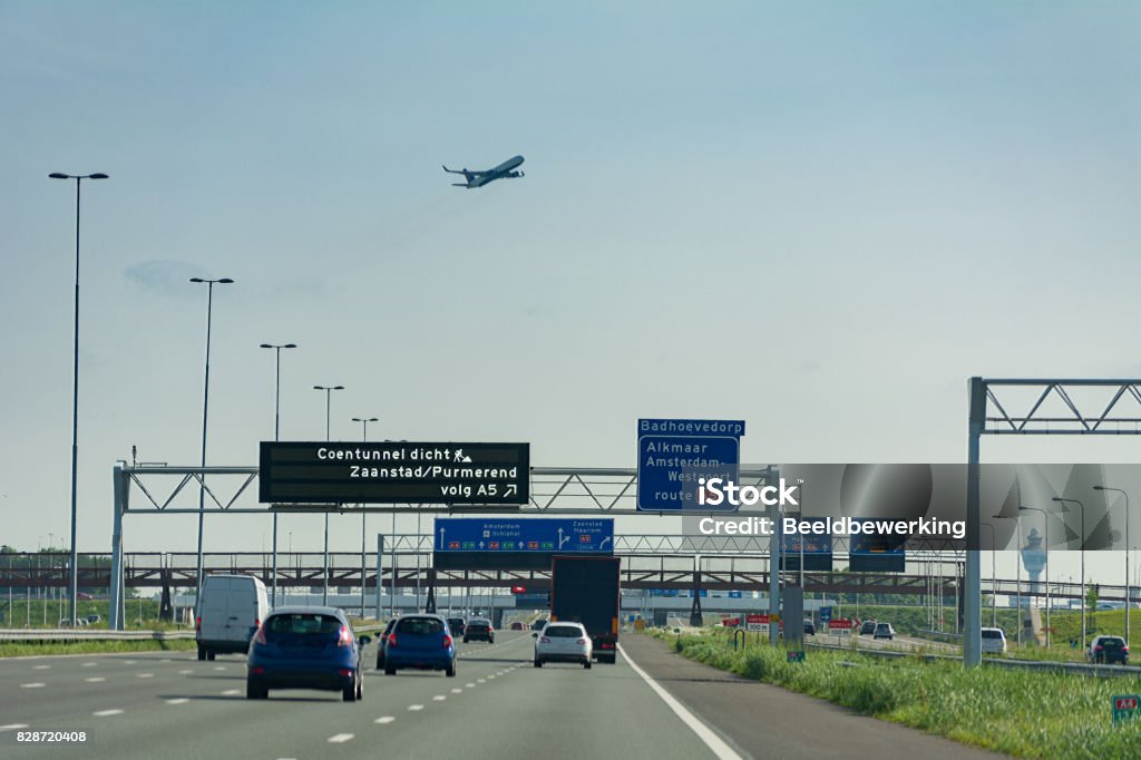Driving on highway next to schiphol Amsterdam Airport Driving on highway next to schiphol Amsterdam Airport with plane overhead and controltower Netherlands Stock Photo