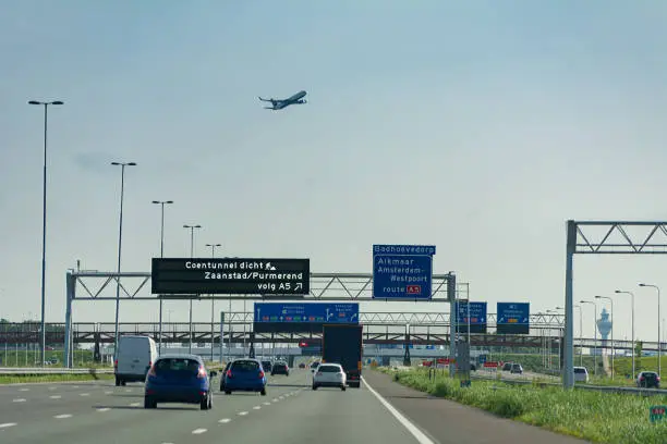 Driving on highway next to schiphol Amsterdam Airport with plane overhead and controltower