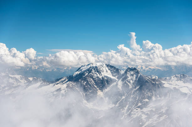 céu azul com nuvens nos picos das montanhas rochosas cobertas com neve e geleiras - mont blanc ski slope european alps mountain range - fotografias e filmes do acervo