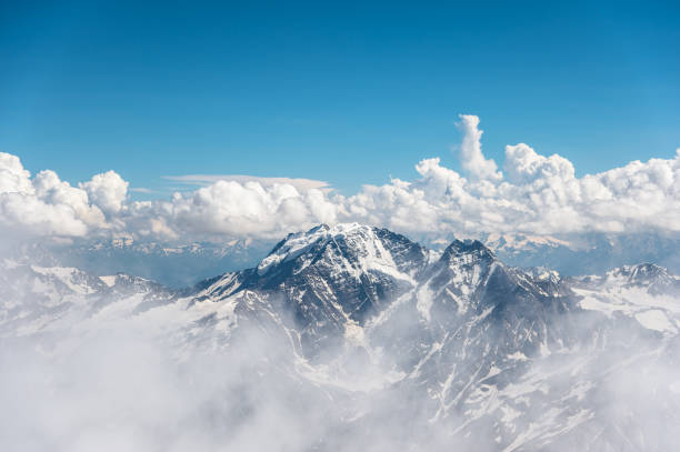 темно-синее небо с облаками на скалистых вершинах гор, покрытых ледниками и снегом - mont blanc ski slope european alps mountain range стоковые фото и изображения