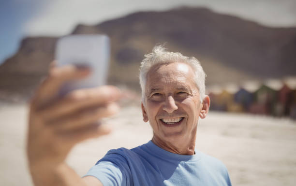 istock Happy senior man taking selfie at beach 828740354