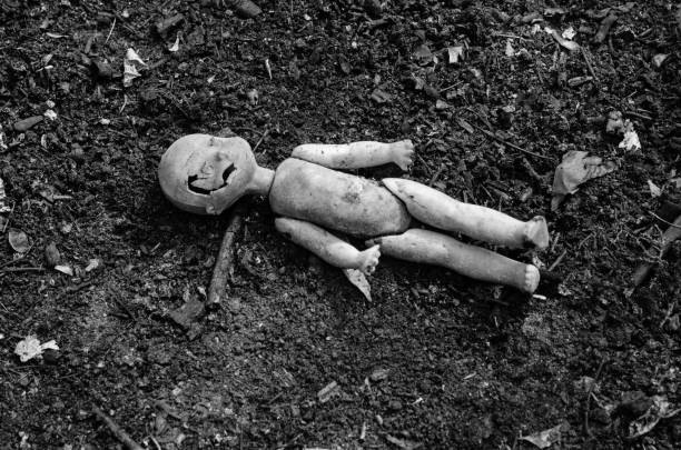 Old broken doll on the pile of the ash stock photo