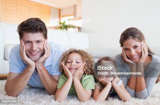 Family Lying On A Carpet Stock Photo - Download Image Now - 20-29 Years, 25-29 Years, 30-34 Years