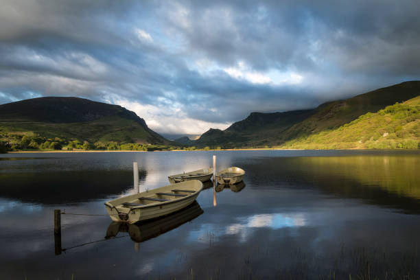 istock Stunning dramatic stormy sky formations over breathtaking mountain lake landscape with rowing boats in foreground 828818186