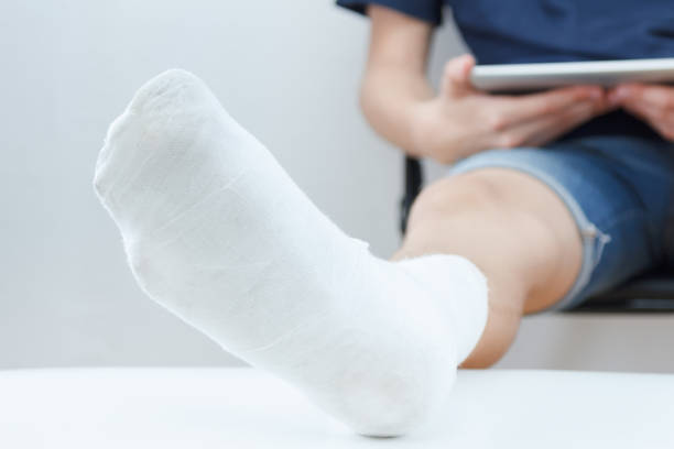 istock Man with broken leg in a plaster with tablet on white background 828820128