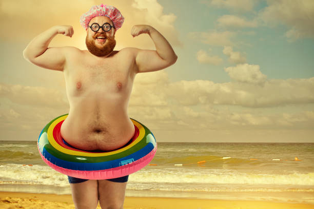 istock Funny fat man in a swimsuit with an inflatable circle on the bea 828826460
