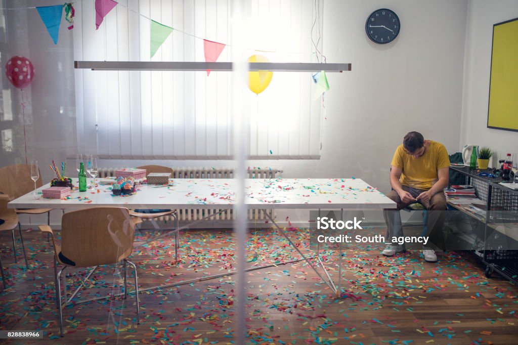 Cleaning mess after party Tired man cleaning messy office after party Party - Social Event Stock Photo