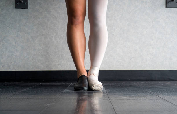 dancer standing in parallel position at the barre, half dress in jazz dance attire and half in ballet attire - jazz ballet imagens e fotografias de stock