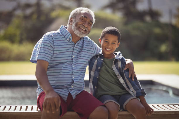 istock Smiling grandfather and grandson sitting together on bench 828878582