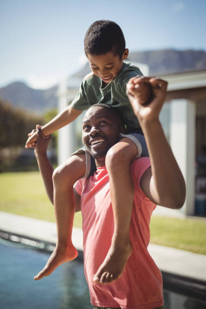 istock Father carrying son on shoulders near poolside 828892200