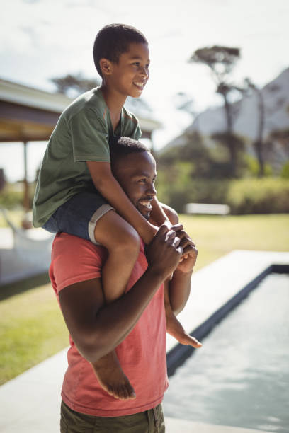 istock Father carrying son on shoulders near poolside 828894452