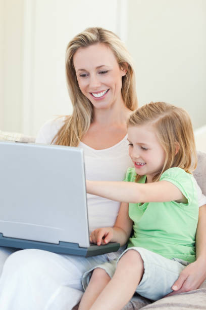 istock Mother and daughter with laptop on couch 828952336