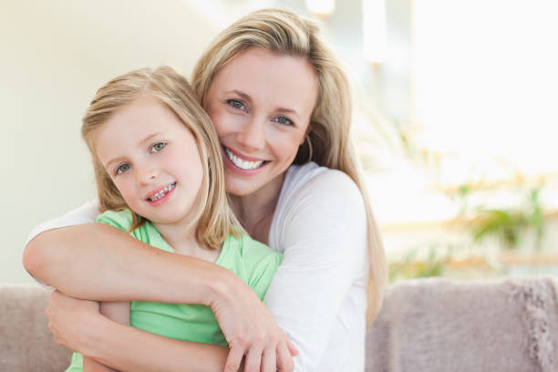istock Mother hugging her daughter on sofa 828952444