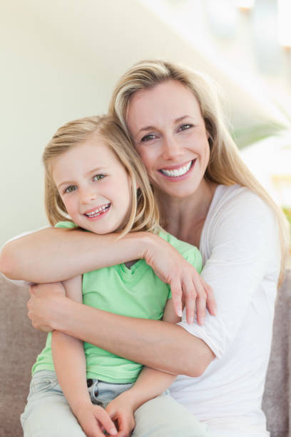 istock Mother hugging her daughter on couch 828952506