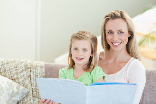 istock Mother and daughter reading a magazine on the sofa 828973142