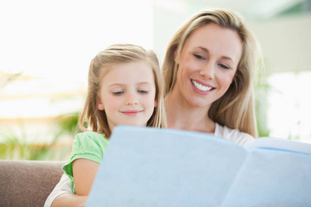 istock Mother and daughter reading a magazine on the couch 828973534