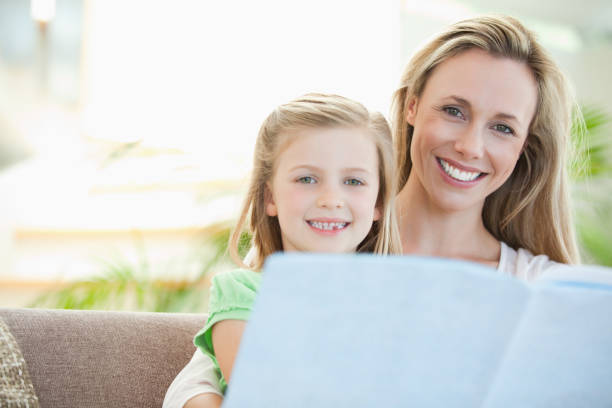 istock Mother and daughter reading on the sofa 828973660