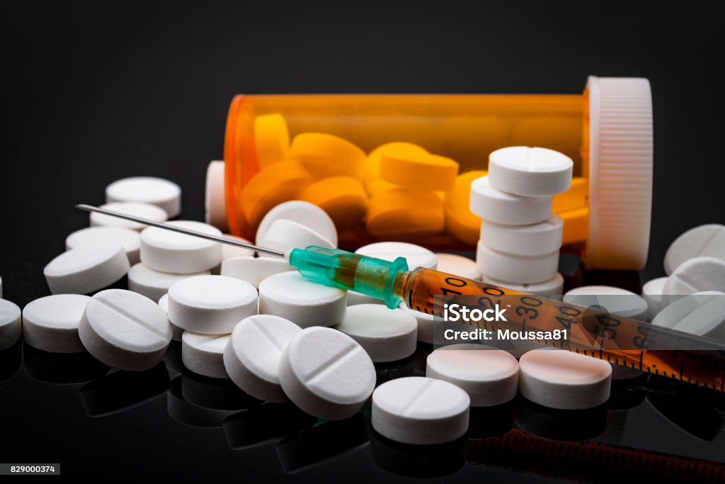Opioid epidemic and drug abuse concept Opioid epidemic and drug abuse concept with a heroin syringe or other narcotic substances next to a bottle of prescription opioids. Oxycodone is the generic name for a range of opioid painkillers Opioid Stock Photo