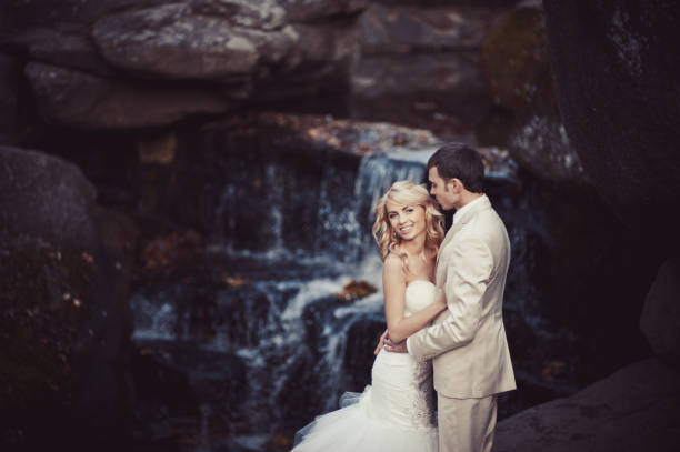istock Wedding couple in white dresses at the waterfall 829005774