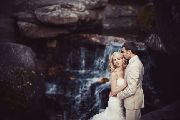 istock Wedding couple in white dresses at the waterfall 829005782