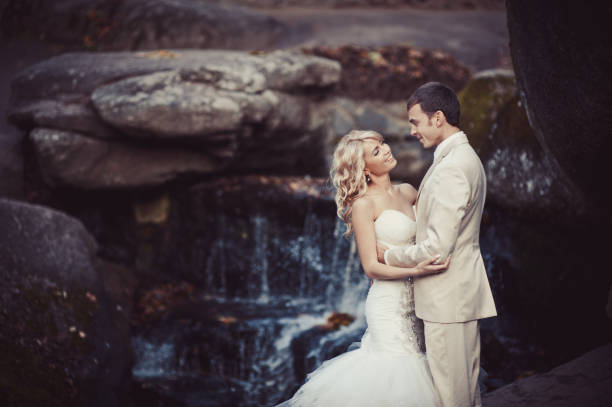istock Wedding couple in white dresses at the waterfall 829005804