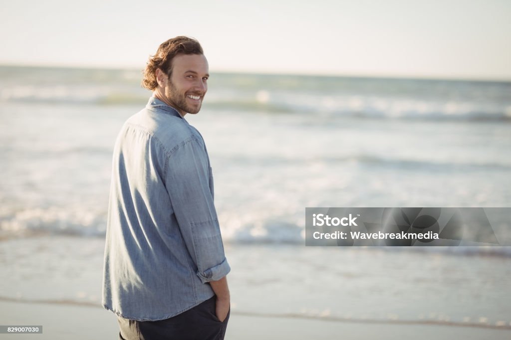 Portrait of smiling young man beach Portrait of smiling young man standing at beach 20-29 Years Stock Photo