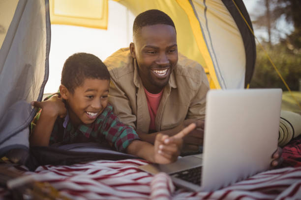 istock Smiling father and son using laptop in tent 829026228