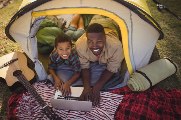 istock Smiling father and son using laptop in tent 829026426