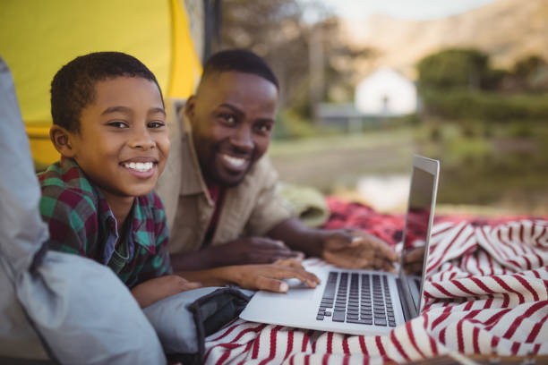 istock Smiling father and son using laptop in tent 829026756
