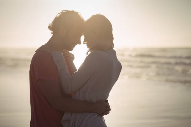 istock Side view of couple embracing at beach 829043300