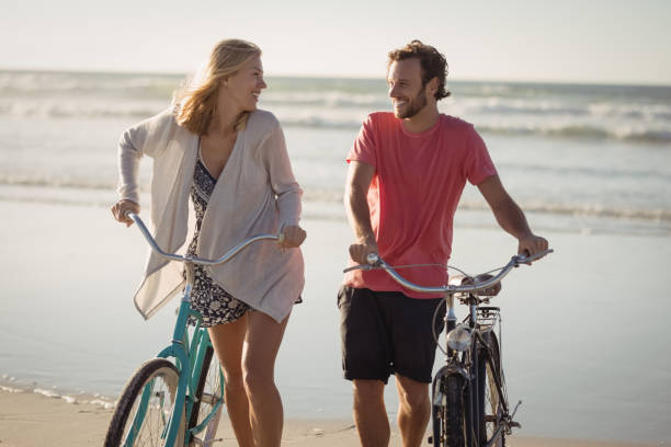 istock Happy couple with bicycles walking at beach 829044408